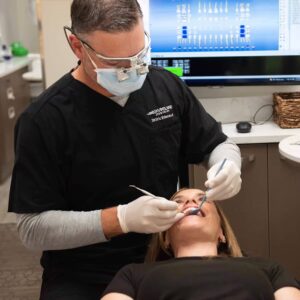 The dentist using a gentle technique and is attentive to the young female patient.