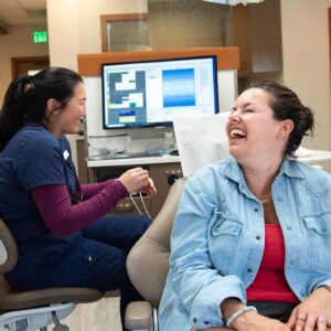 Dental office staff laughing with a dental patient.